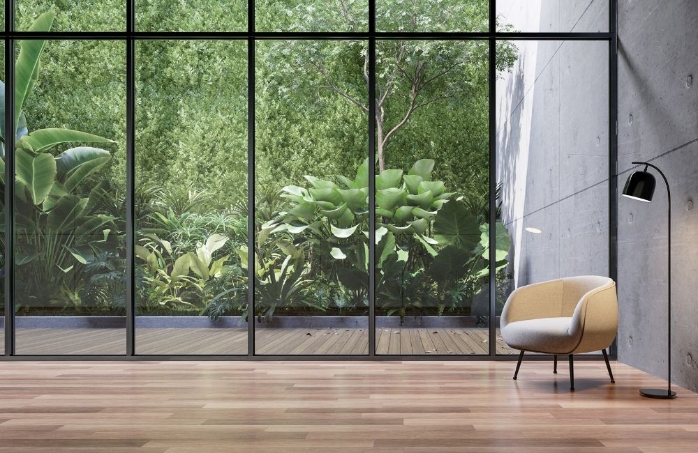 Modern minimalist living room with floor-to-ceiling windows looking out to lush greenery